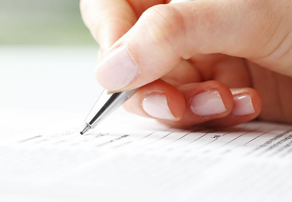 Closeup of female hand with pen filling out corporate document