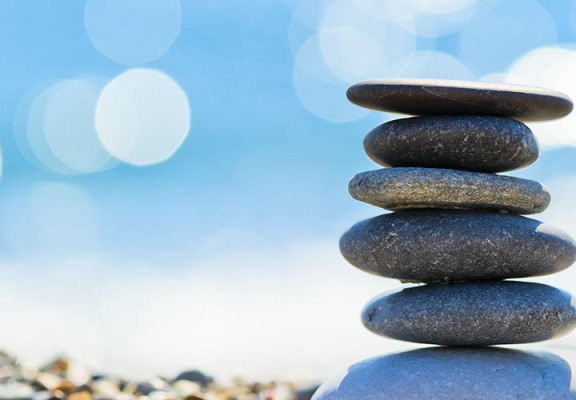 Flat rocks piled and balanced on water shoreline