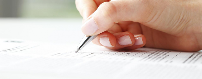 Closeup of female hand with pen filling out corporate document