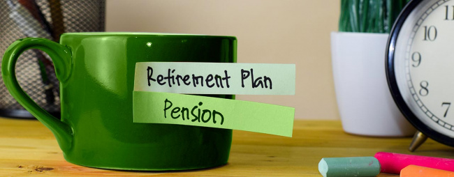 Cup of coffee on top of desk with sticky notes reading, retirement plan and pension.